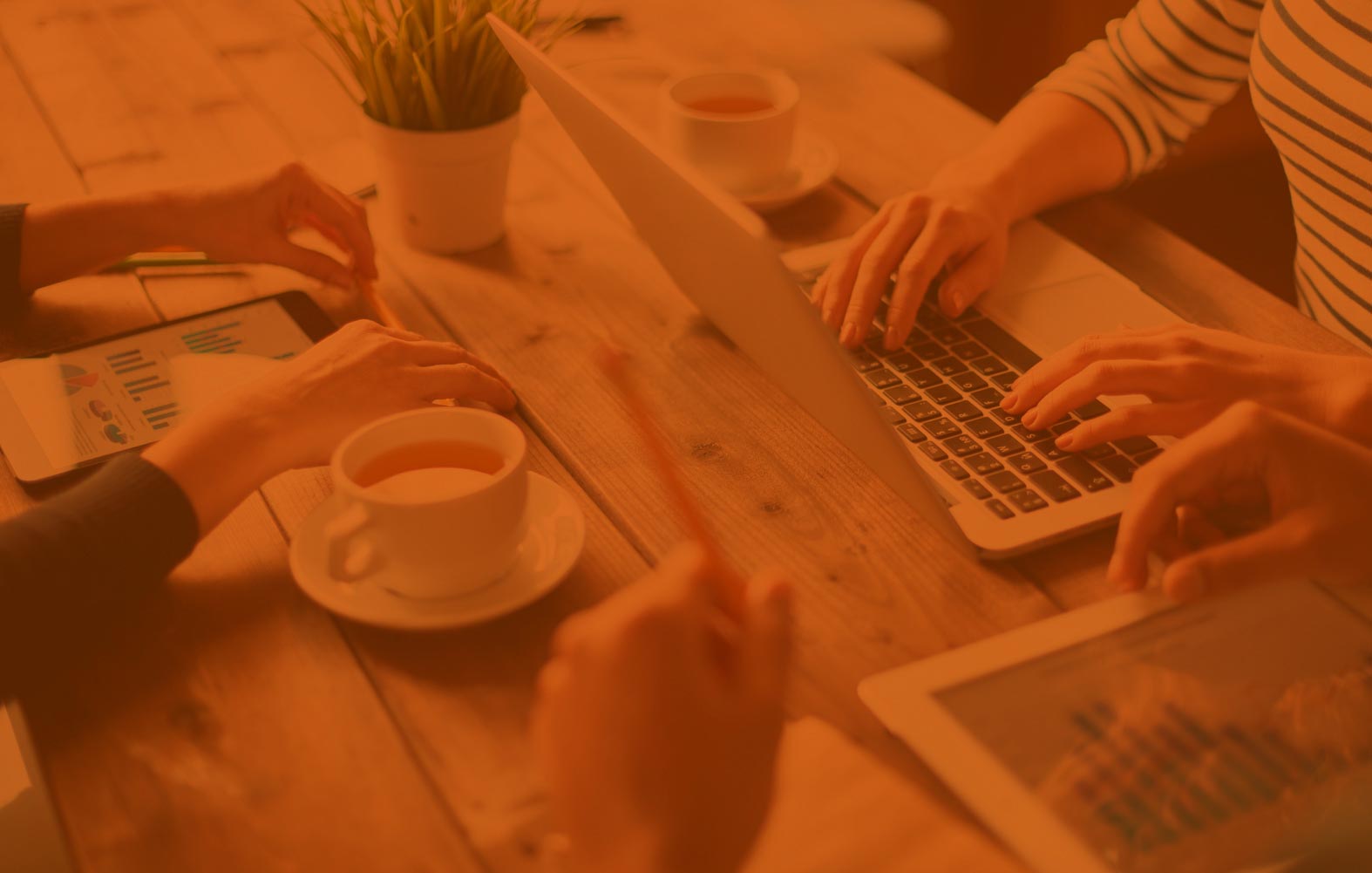 people at table, working on their laptop and tablet